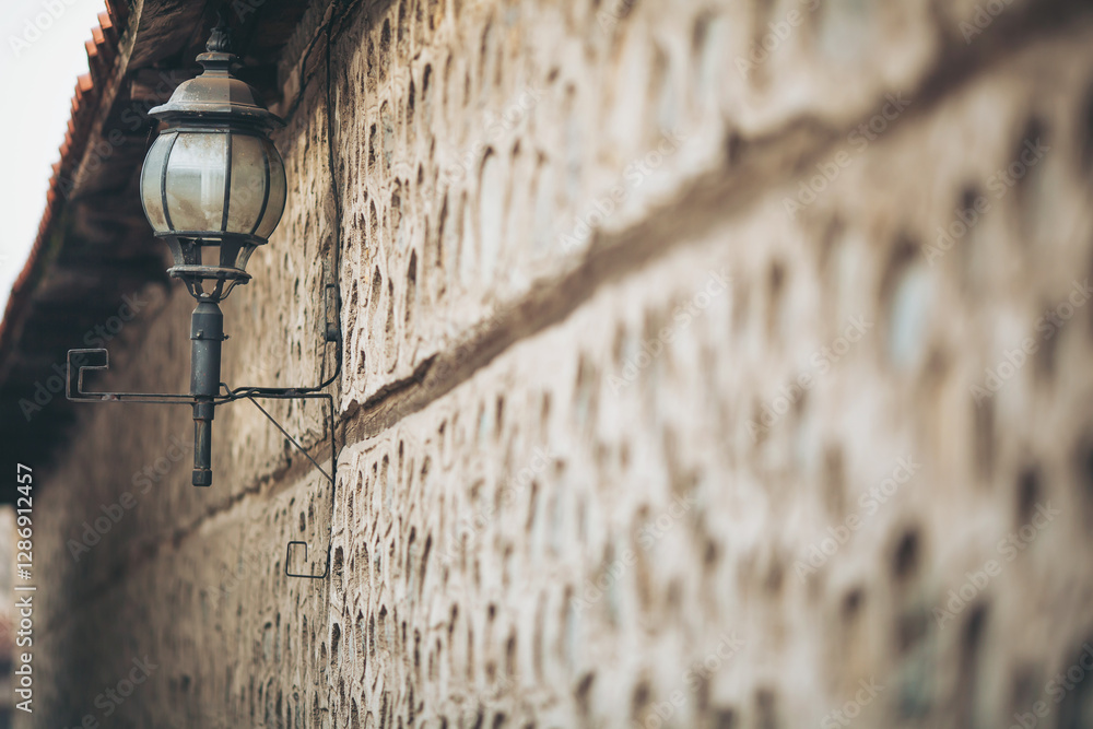 A quaint lantern hangs from a rough stone wall, casting a warm glow on the weathered surface. Soft afternoon light enhances the rustic charm of the scene, evoking a sense of nostalgia A quaint lantern hangs from a rough stone wall, casting a warm glow on the weathered surface. Soft afternoon light enhances the rustic charm of the scene, evoking a sense of nostalgia