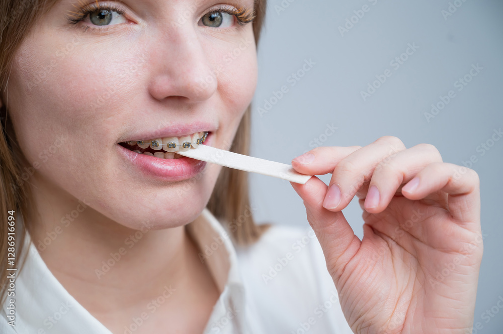 Young woman with metal braces on her teeth is chewing gum. The girl is eating gummy candy Young woman with metal braces on her teeth is chewing gum. The girl is eating gummy candy