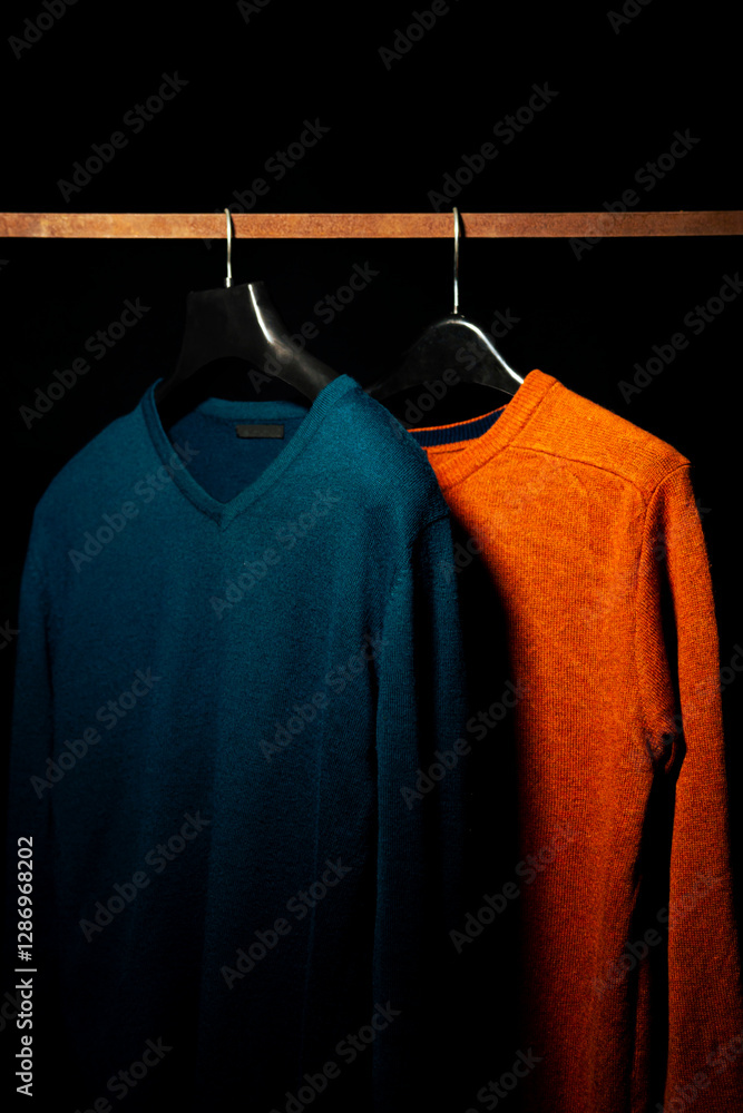 Obraz premium Plain Orange And Teal Sweatshirts on Hanger, Isolated on Black Background