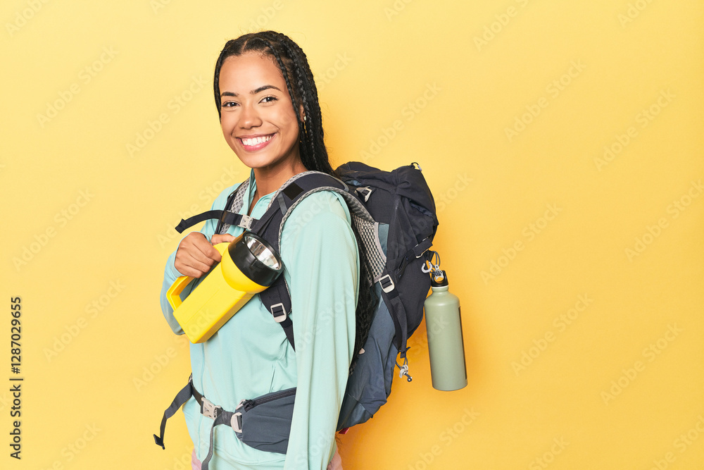 Indonesian hiker holding flashlight on yellow backdrop Indonesian hiker holding flashlight on yellow backdrop