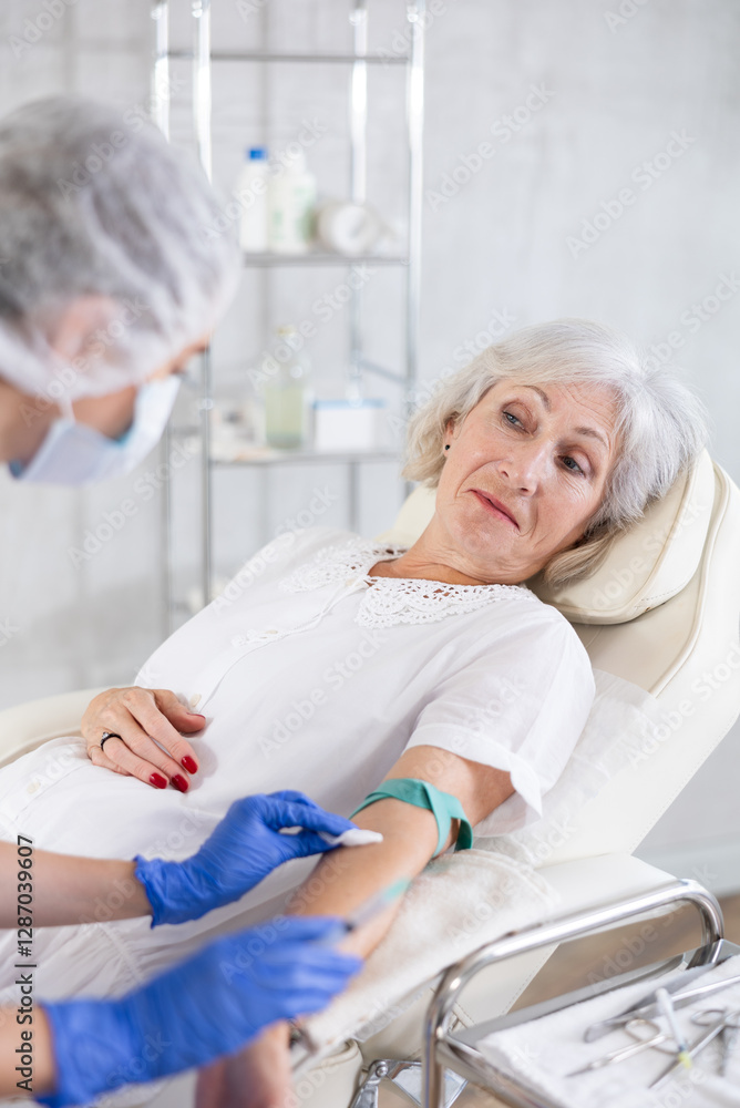 Obraz premium Adult woman with grey hair is receiving injecting hypodermic against covid or flu.