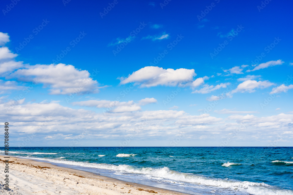 Fototapeta premium waves crashing on beach with clouds in blue sky