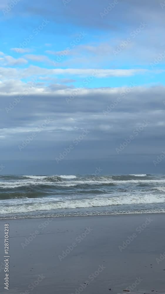 Ocean Waves Crashing on the Shore with Blue and Grey Clouds Ocean Waves Crashing on the Shore with Blue and Grey Clouds