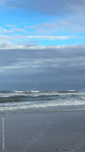 Ocean Waves Crashing on the Shore with Blue and Grey Clouds 