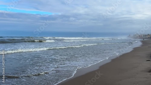 Waves Rolling onto a Misty Beach with Urban Skyline