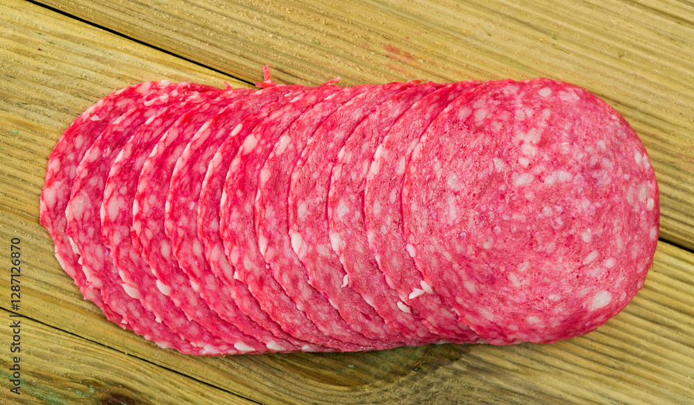 Photography Appetizing slices of popular Italian salami on wooden surface..