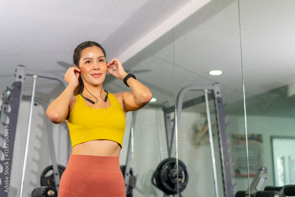 Wellness Health Technology. Healthy Asian woman do sport training fitness workout exercise at gym. Sporty girl in sportswear using smartwatch health app and listening to music on earphones at stadium. Wellness Health Technology. Healthy Asian woman do sport training fitness workout exercise at gym. Sporty girl in sportswear using smartwatch health app and listening to music on earphones at stadium.