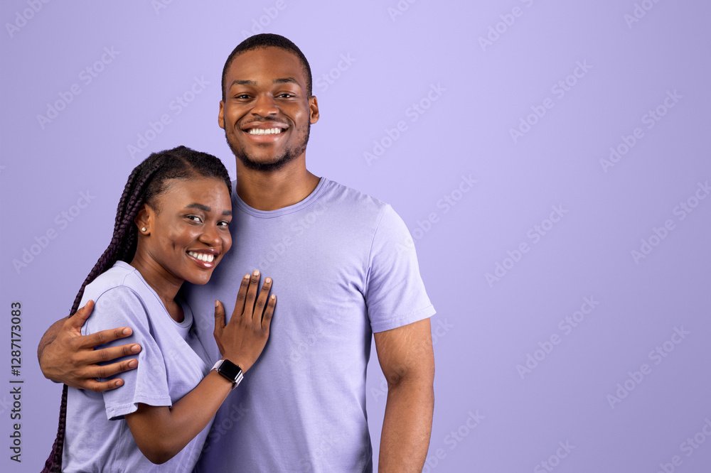 Obraz premium Love, Care And Tenderness. Portrait of smiling African American woman and man hugging, enjoying time together, standing isolated over purple studio background, posing and looking at camera