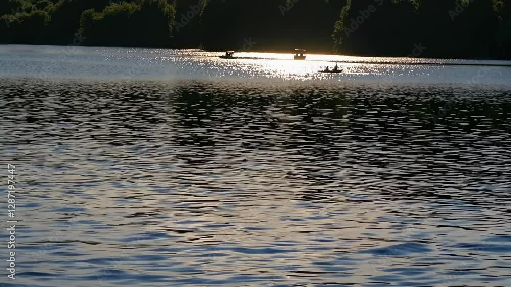 A serene lake at sunset with shimmering water, captured from a low angle. The video highlights tranquil nature and peaceful reflections. A serene lake at sunset with shimmering water, captured from a low angle. The video highlights tranquil nature and peaceful reflections.
