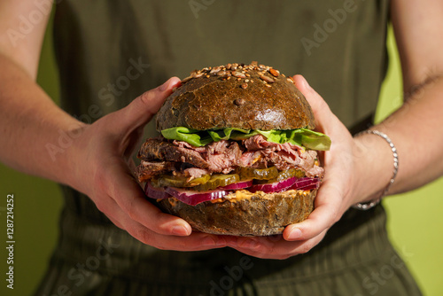 Photos Roast Beef Sandwich, fresh lettuce, pickles, red onion, held person's hands, wit