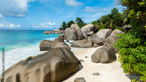 Turquoise waters washing over a white sandy beach with rocks. Seychelles, Mahe. Carana beach.