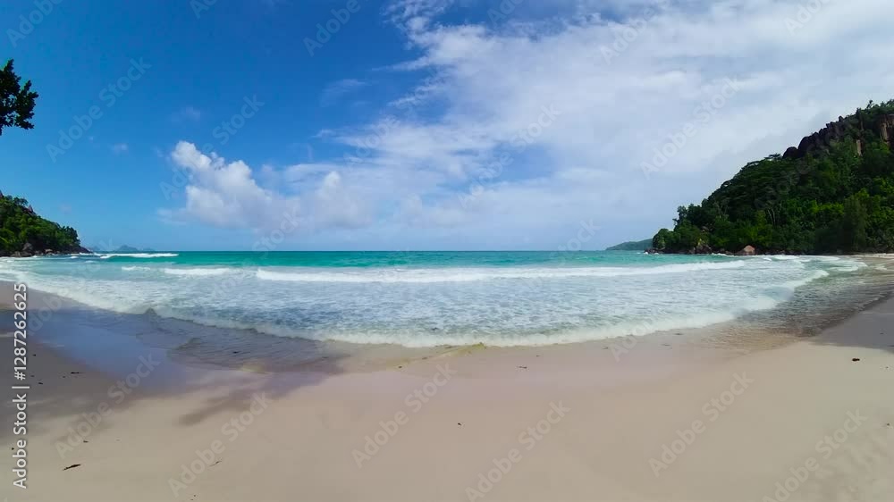 A beautiful beach with white sand, turquoise ocean, and green cliffs under a blue sky. Seychelles, Mahe. Anse Louis. A beautiful beach with white sand, turquoise ocean, and green cliffs under a blue sky. Seychelles, Mahe. Anse Louis.