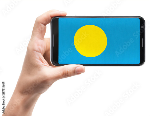 パラオの国旗が画面に表示されているスマートフォンを持つ手。白背景。(Hand holding smartphone, screen is Palau flag. on white background.)
 photo