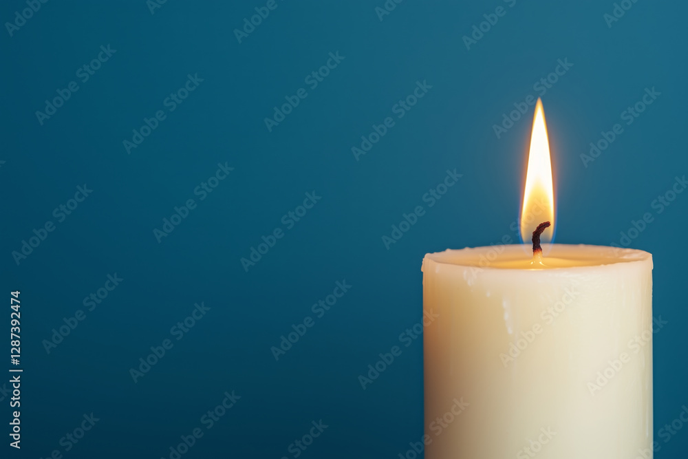Single lit white candle with a soft flame against a dark teal background Single lit white candle with a soft flame against a dark teal background