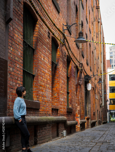 Tableau sur toile Side view of a woman exploring the city laneway, at Niagara Lane, Melbourne, Aus