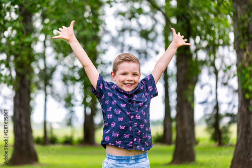 Portrait of kindergarten aged boy outdoors smiling with arms wide in celebration of success photo