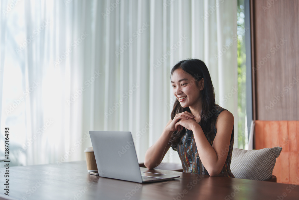 Happy young asian woman working remotely at a wooden table in a modern cafe, enjoying takeaway coffee while browsing on her laptop, smiling and embracing a cozy, relaxed atmosphere Happy young asian woman working remotely at a wooden table in a modern cafe, enjoying takeaway coffee while browsing on her laptop, smiling and embracing a cozy, relaxed atmosphere