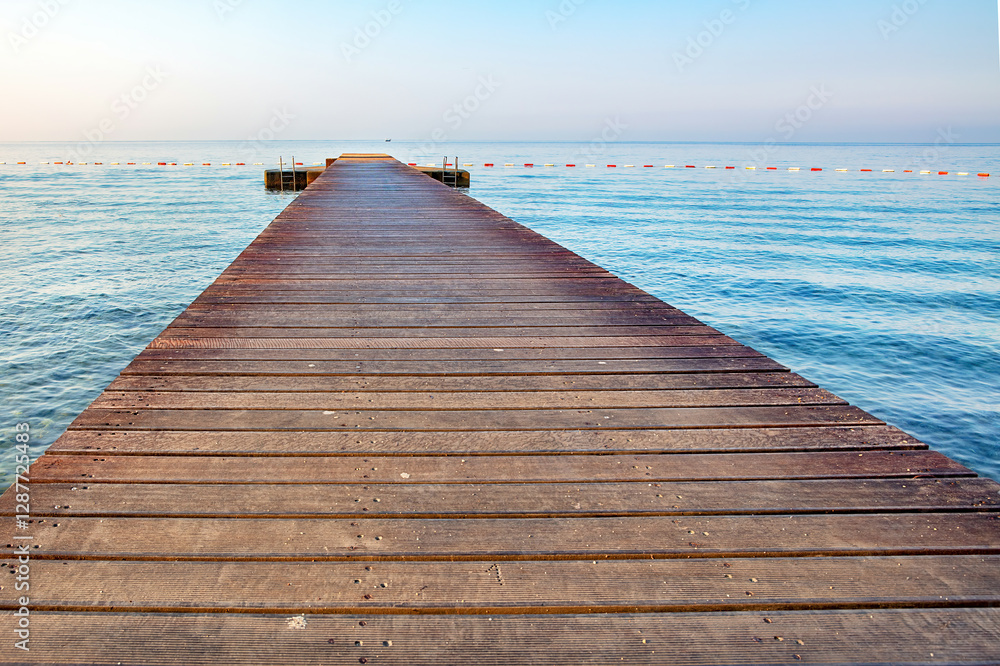 Serene wooden pier stretches into calm waters during early morning light