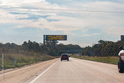 Wear a seatbelt correctly penalties apply digital sign above highway photo