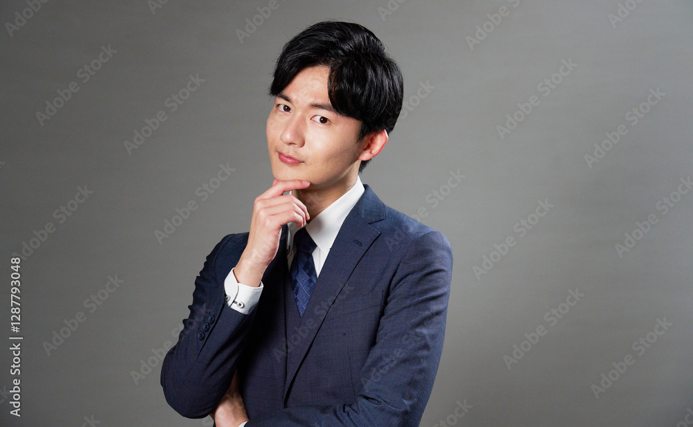 ビジネスマン　考える　黒背景　カメラ目線