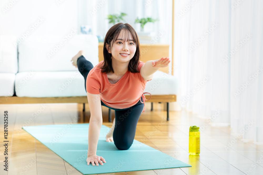 Fototapeta premium リビングでヨガをする若い女性