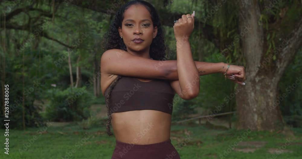 A health-focused woman stretches and jogs in a wooded park. A health-focused woman stretches and jogs in a wooded park.