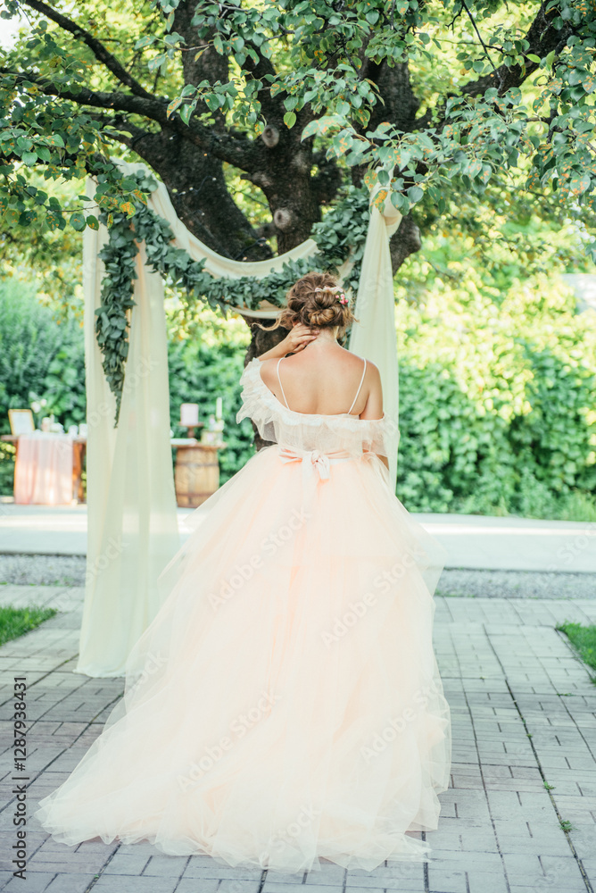 Fototapeta premium A bride in a soft pastel wedding gown sits on a decorated wooden chair labeled