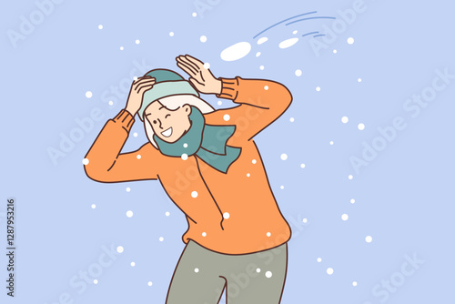 Happy woman plays snowball and dodges snow flying at head, rejoicing in arrival of winter days