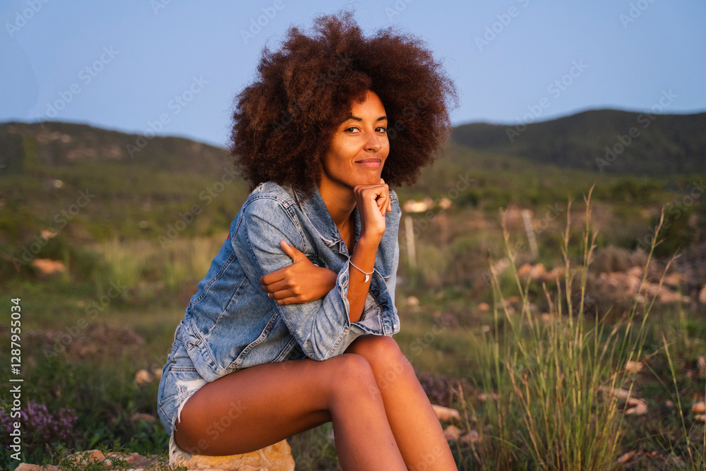 Young woman sitting on stone, chin on hand Young woman sitting on stone, chin on hand
