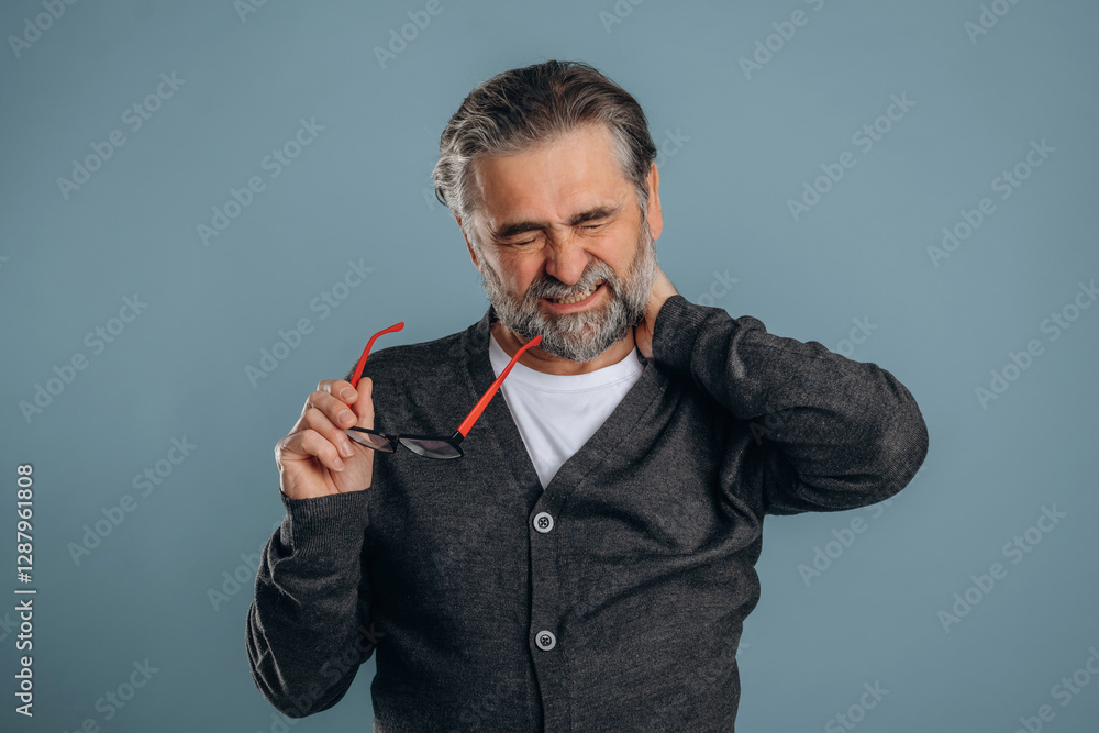 Neck pain. Senior man is standing in the studio against background Neck pain. Senior man is standing in the studio against background