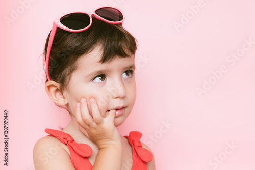 Portrait of pensive little girl in front of pink background photo