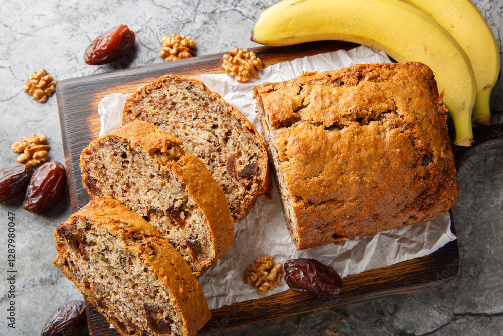 Gluten free and lactose free Date banana walnuts bread loaf close up on wooden board on table. Horizontal top view from above
