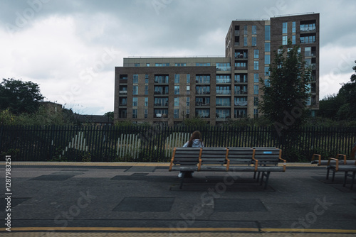 Quiet train station with benches and modern residential buildings in the background. A moody atmosphere highlights urban solitude. photo