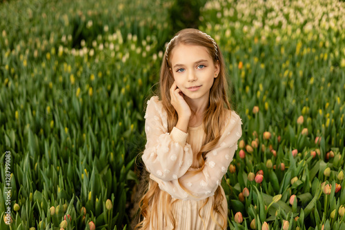 A cute charming girl in a light dress is photographed in a greenhouse with tulip flowers. Women's Day photo