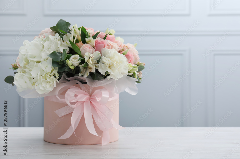 Beautiful bouquet in box on white wooden table against light wall. Space for text Beautiful bouquet in box on white wooden table against light wall. Space for text