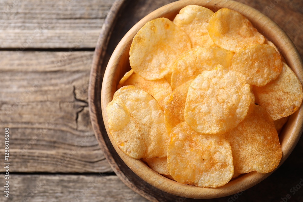 Tasty potato chips in bowl on wooden table, top view. Space for text Tasty potato chips in bowl on wooden table, top view. Space for text