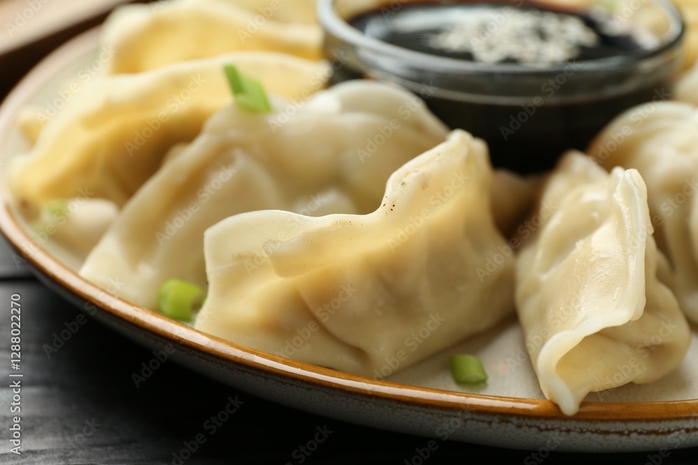 Tasty boiled gyoza (dumplings) with green onion and soy sauce on black table, closeup Tasty boiled gyoza (dumplings) with green onion and soy sauce on black table, closeup