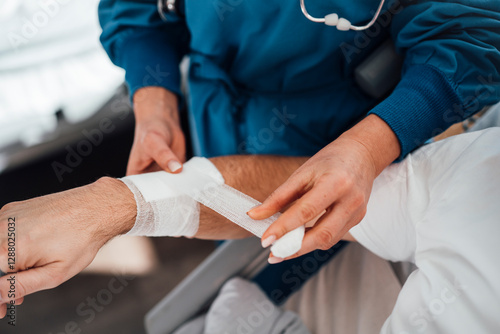 Doctor bandaging a patient's arm during a medical consultation in a clinic