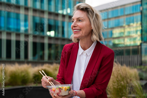 Businesswoman eating poke with chopsticks in an urban setting