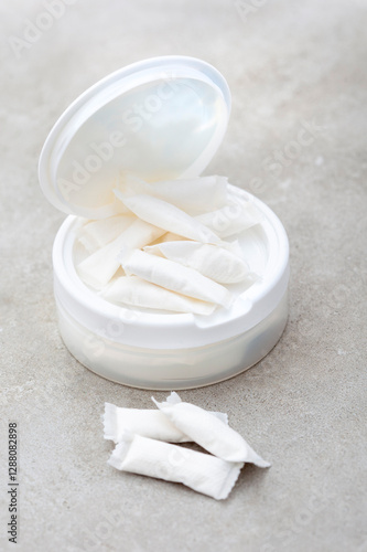 a white container of nicotine pouches on a grunge gray surface