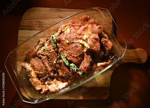Obraz na płótnie Marinated meat prepared for grilling on a wooden cutting board with fresh herbs and spices w salonie