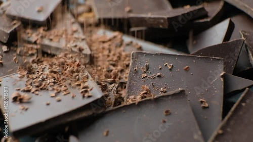 Chocolate chips pour on pieces of dark organic chocolate slow motion