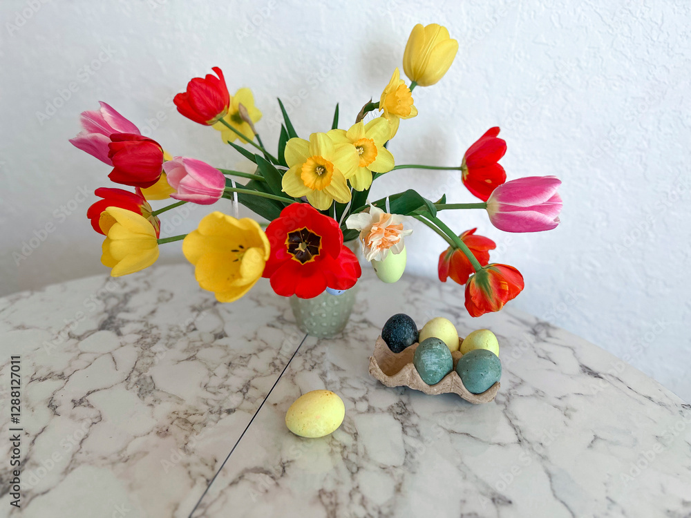 An Easter card. Colorful bright tulips decorated with eggs stand in a vase on the table next to colorful eggs
