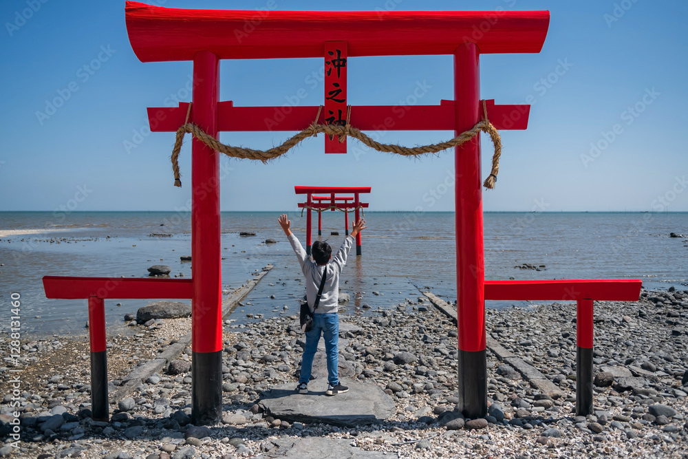Japanese young boy raises hands at red torii gate of Oouo Shrine, Tara Japanese young boy raises hands at red torii gate of Oouo Shrine, Tara