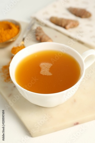 Aromatic turmeric tea, powder and rhizomes on white table, closeup