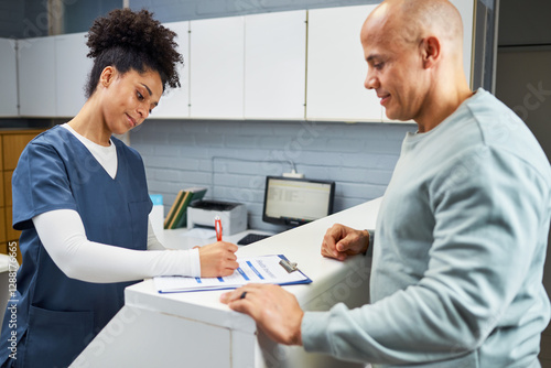 Healthcare Worker Assisting Patient at Reception Desk with Forms in Modern Medical Facility