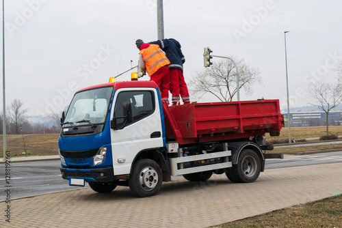 Dump truck with workers on the road. Construction truck on the street. Road work with dump truck and workers