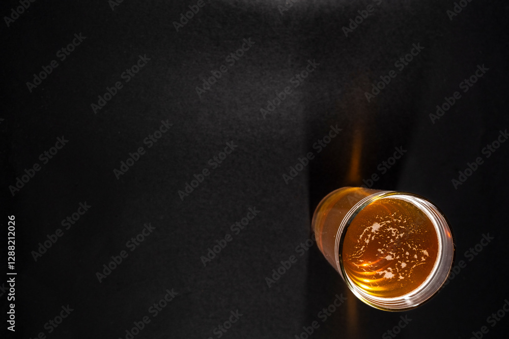 glass of golden beer with a frothy head is placed slightly to the right on a black chalkboard background, with empty space on the left