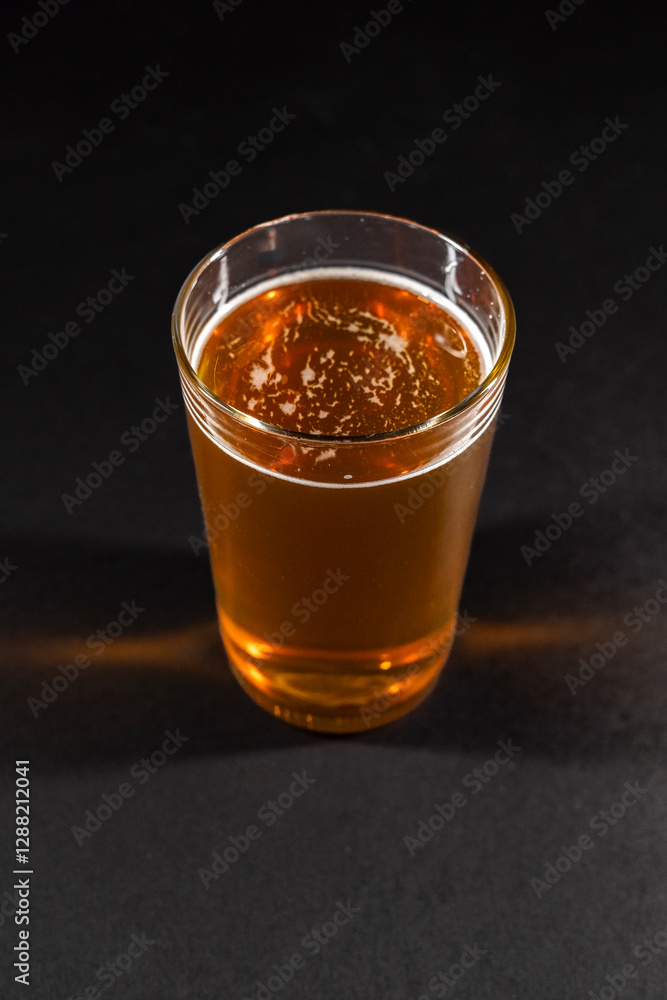 beer mug filled with foamy amber beer is positioned to the left on a black chalkboard background, leaving empty space on the right