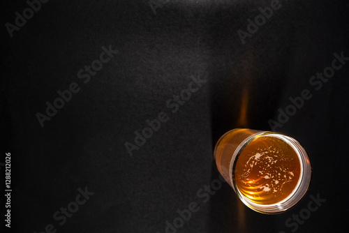 Obraz na płótnie glass of golden beer with a frothy head is placed slightly to the right on a black chalkboard background, with empty space on the left w salonie